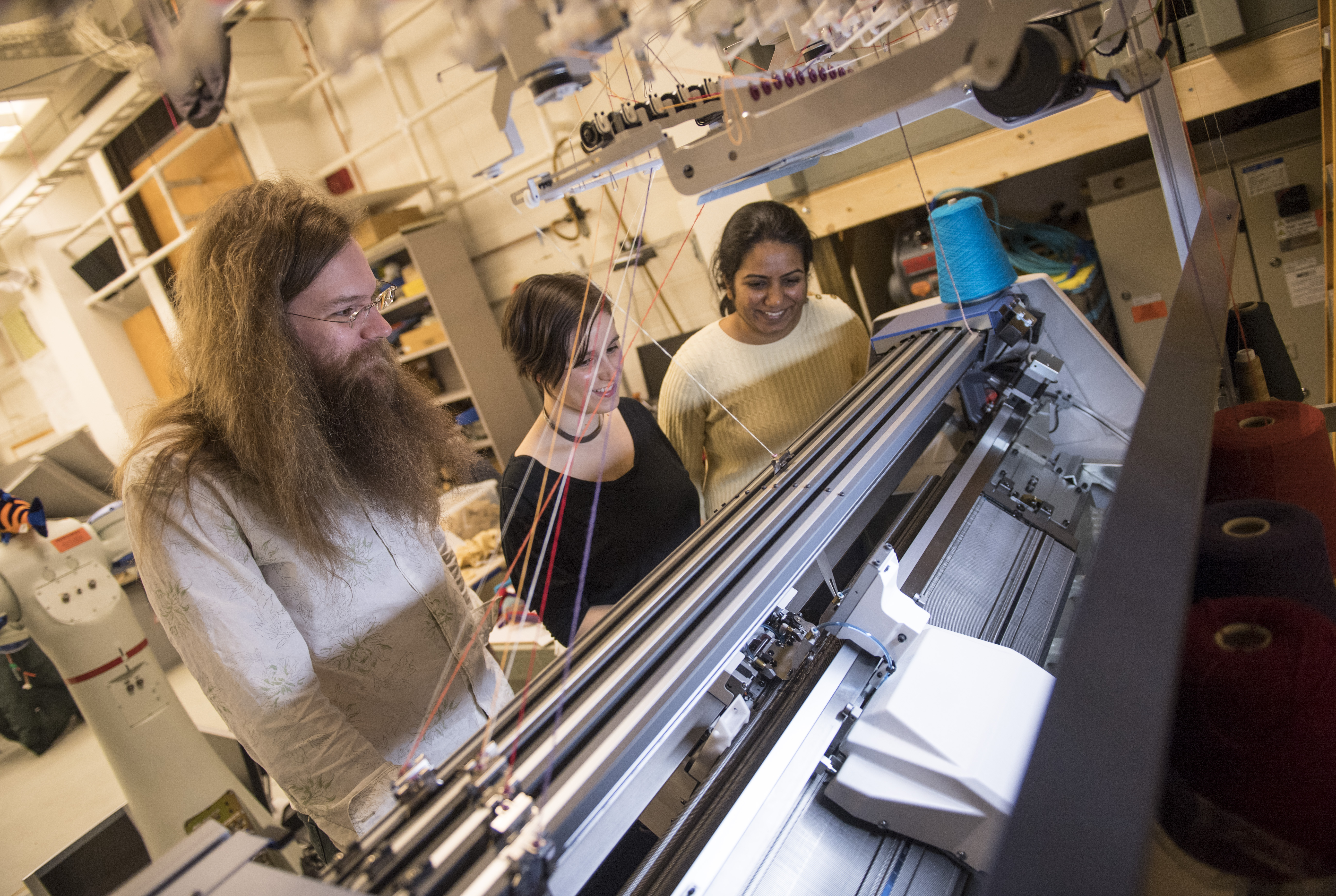 Photo shows James McCann, assistant professor of robotics; Lea Albaugh, Ph.D. student in Human-Computer Interaction Institute, and Vidya Narayanan, Ph.D. in the Computer Science Department, with their knitting machine