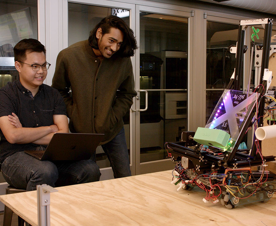 Two students watch their mechatronics class robot in action.