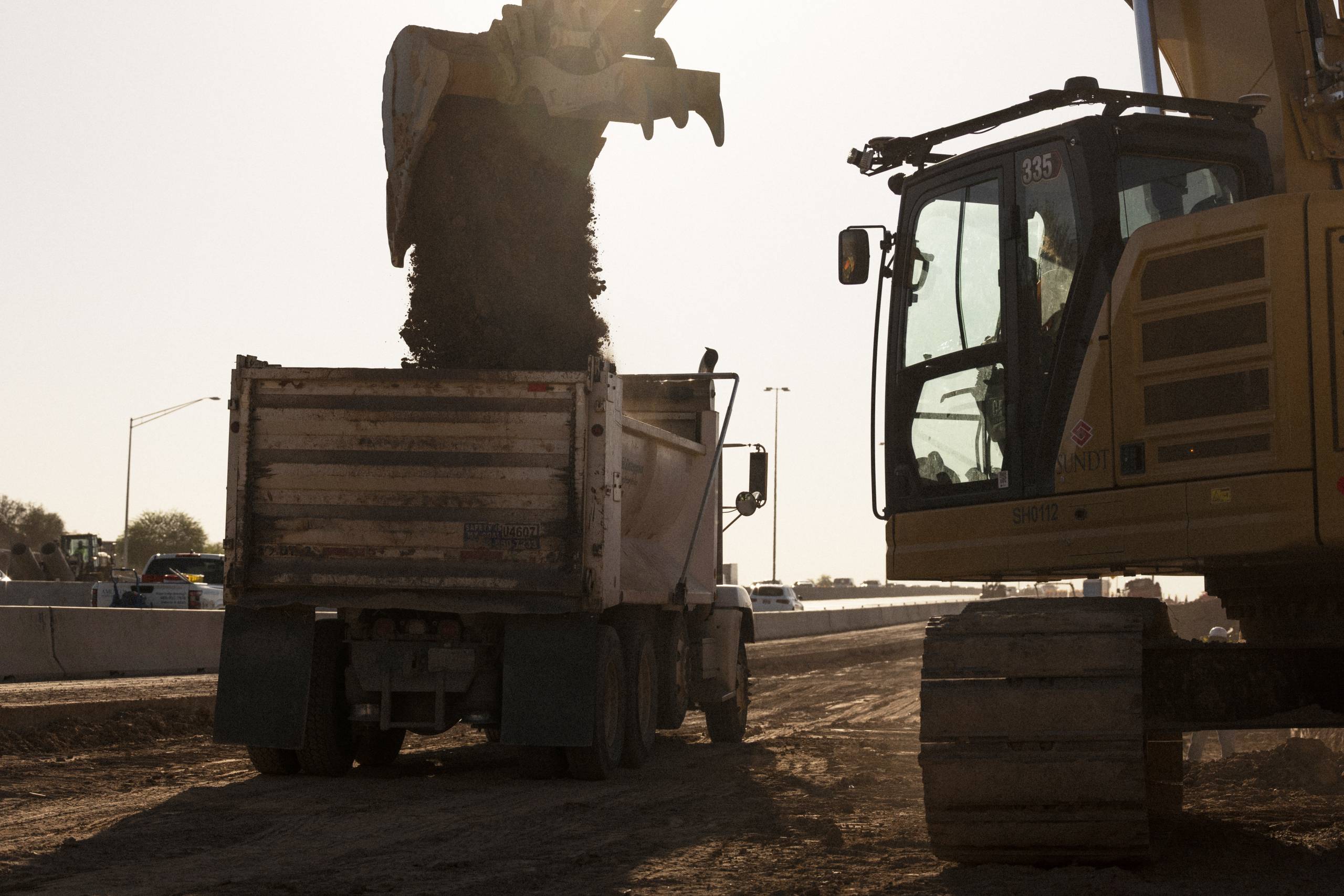 construction equipment drumping dirt into the back of a truck